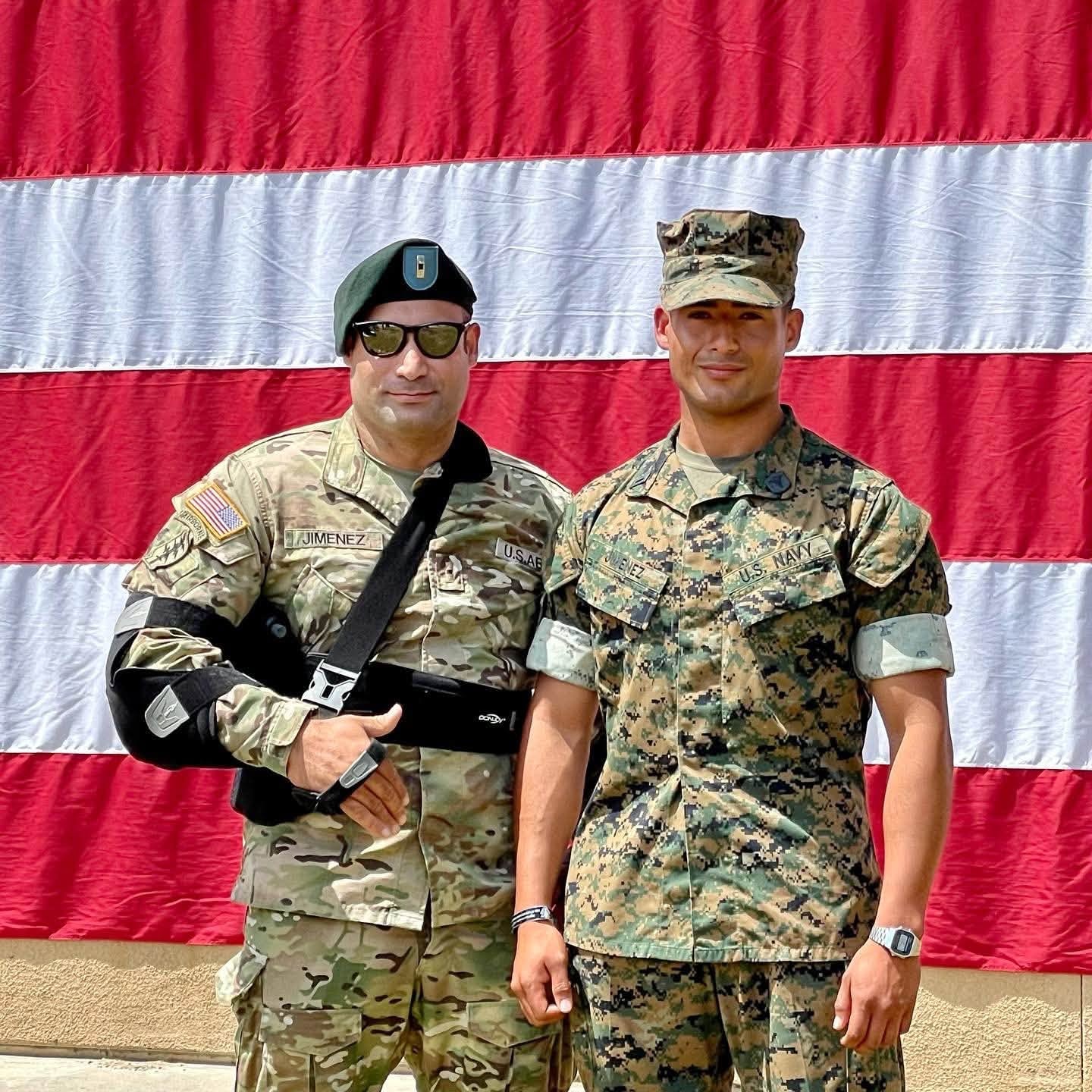 Sam in Green Beret uniform with his son in Navy uniform in front of an American flag